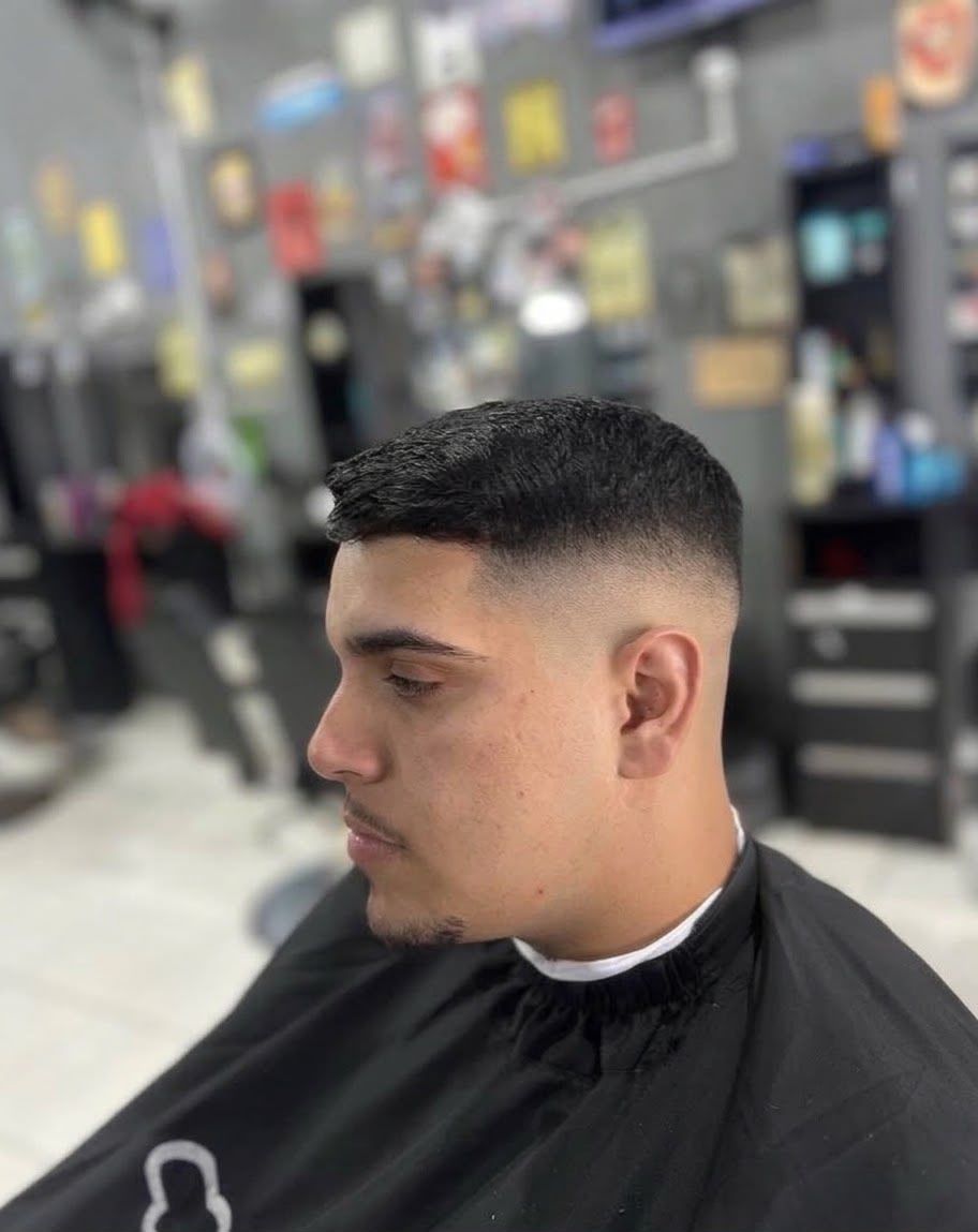 Cliente de perfil com degradê baixo e a linha da testa marcada na navalha